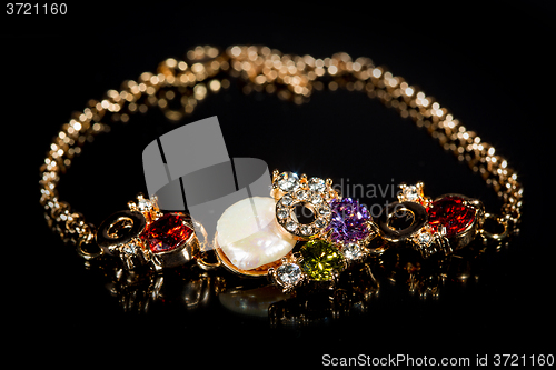 Image of golden bracelet with precious stones on black background