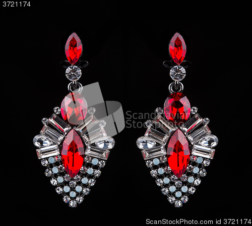 Image of earring with colorful red gems on black background