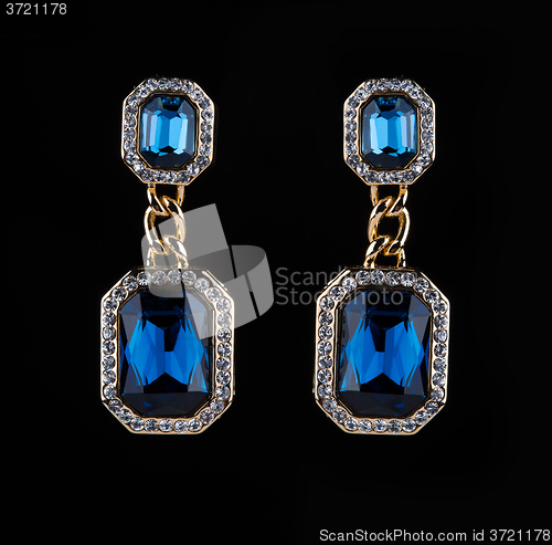 Image of earring with colorful blue gems on black background