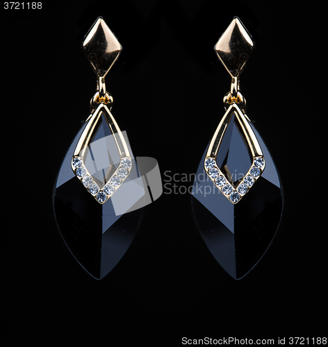 Image of earring with colorful black gems on black background