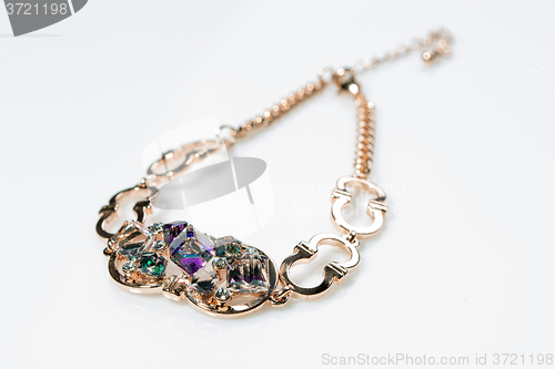 Image of golden bracelet with precious stones on grey background