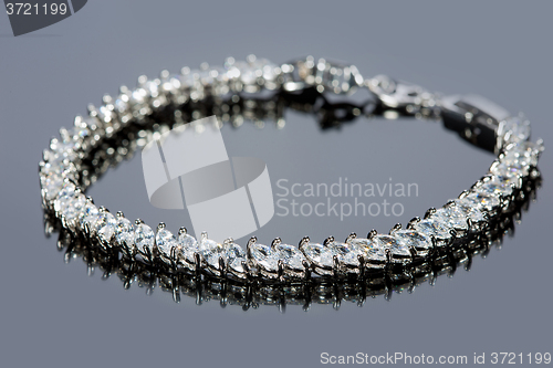 Image of silver bracelet with diamonds on gray background. 