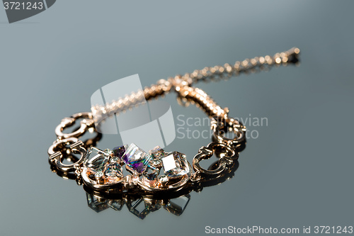 Image of golden bracelet with precious stones on grey background