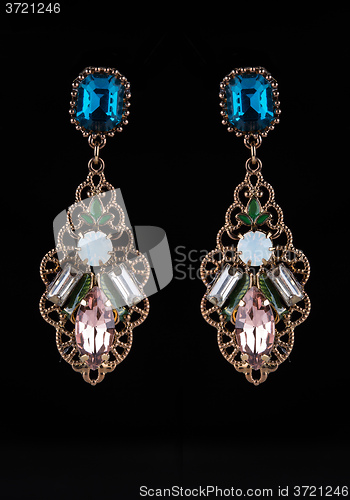 Image of gold earrings with jewels on the black