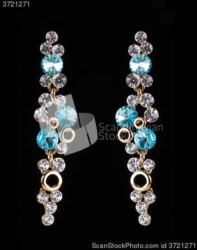 Image of earring with colorful blue gems on black background