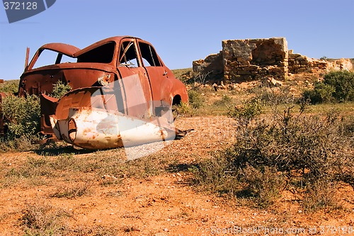 Image of an old rusting car and ruins in the desert