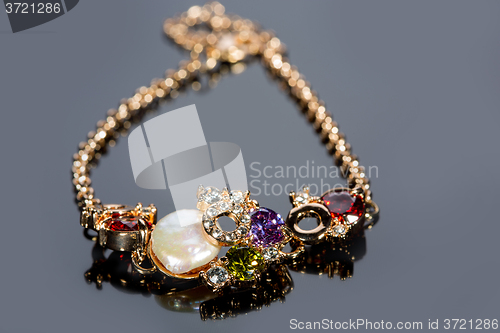 Image of golden bracelet with precious stones on grey background