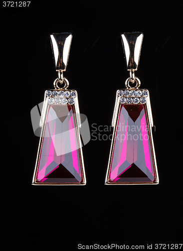 Image of earring with colorful pink gems on black background