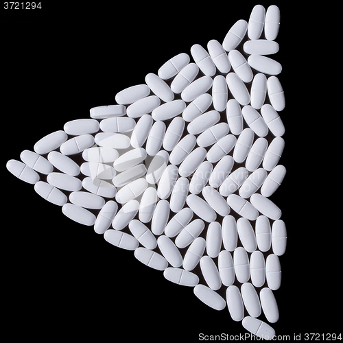 Image of White pills on the black. Triangle of tablets.