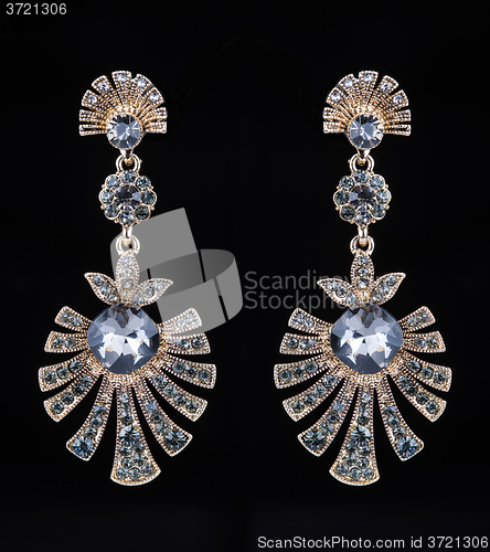 Image of gold earrings with jewels on the black
