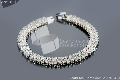 Image of golden bracelet with precious stones on grey background