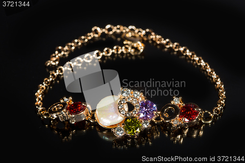 Image of golden bracelet with precious stones on black background