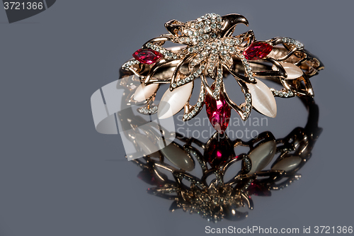 Image of golden bracelet with precious stones on grey background