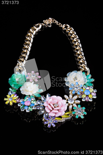 Image of luxury necklace of plastic flowers on black stand