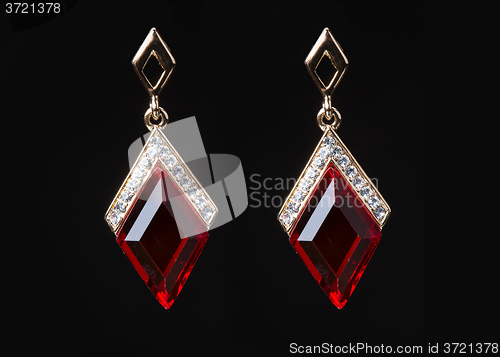 Image of earring with colorful red gems on black background