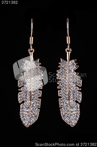 Image of gold earrings with jewels on the black