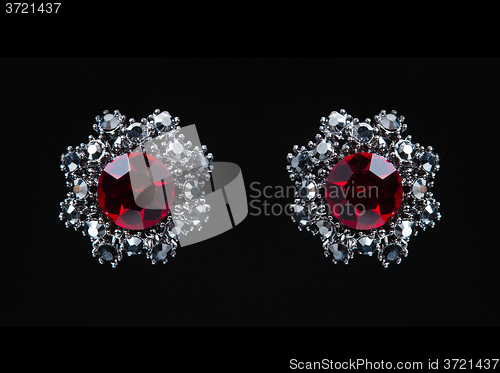 Image of earring with colorful red gems on black background