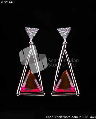 Image of earring with colorful red gems on black background