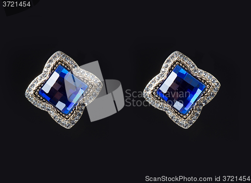 Image of earring with colorful blue gems on black background