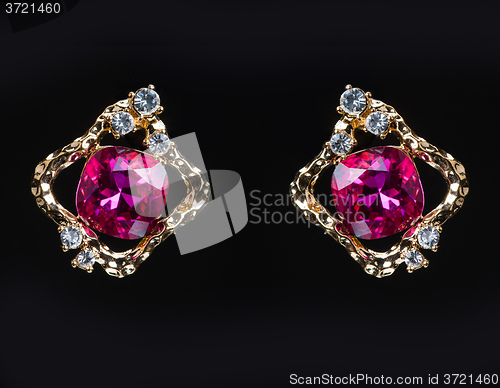 Image of earring with colorful pink gems on black background