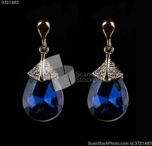 Image of earring with colorful blue gems on black background