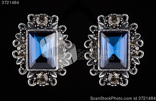 Image of earring with colorful blue gems on black background