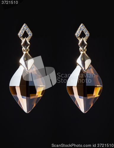 Image of gold earrings with jewels on the black