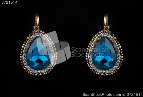 Image of earring with colorful blue gems on black background