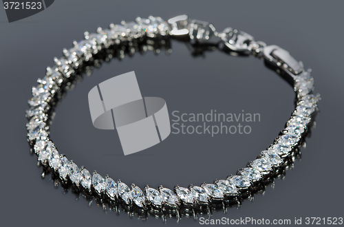 Image of silver bracelet with diamonds on gray background. 