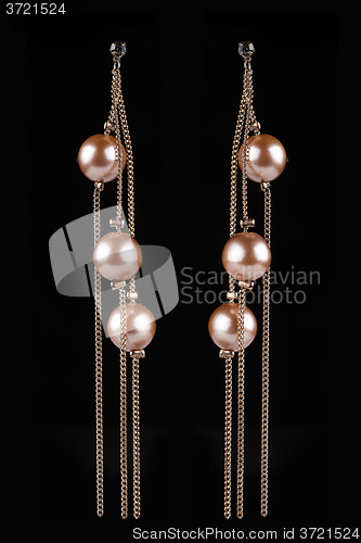 Image of gold earrings with jewels on the black
