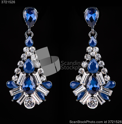 Image of earring with colorful blue gems on black background