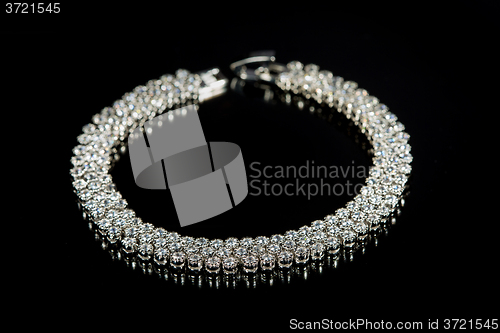 Image of golden bracelet with precious stones on black background