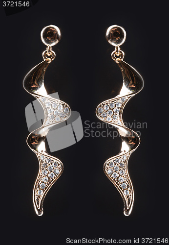 Image of gold earrings with jewels on the black