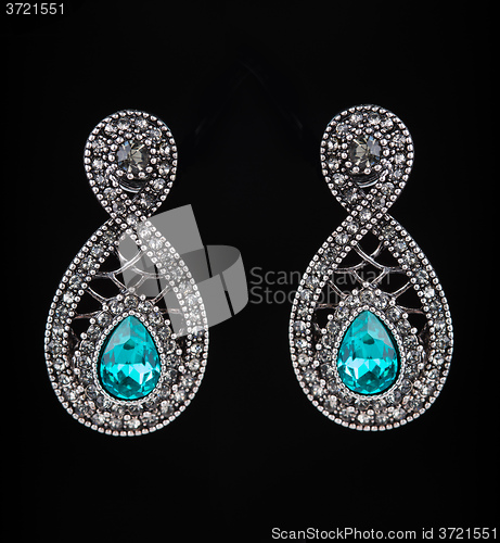 Image of earring with colorful blue gems on black background