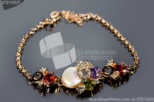 Image of golden bracelet with precious stones on grey background