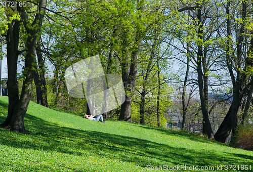 Image of Young people relaxing in the park on the grass 