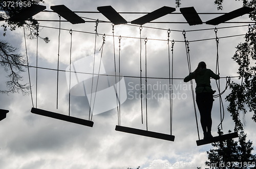 Image of Silhouette of the girl on Dangerous ropeway with tether in rope 