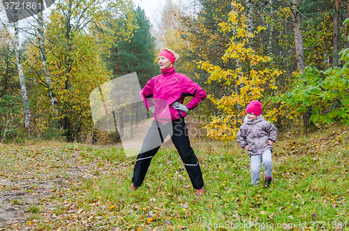 Image of Woman with girl doing aerobics in the autumn park