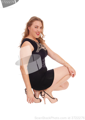 Image of Smiling woman crouching on floor.