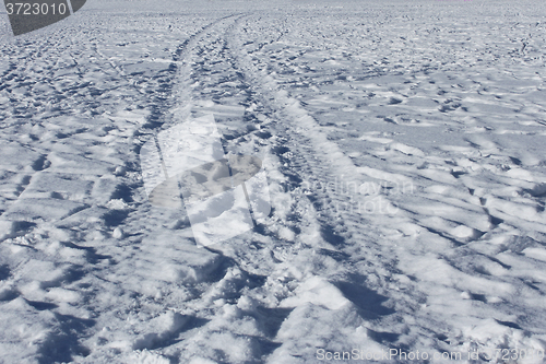 Image of Wheel track and human footprints on the snow