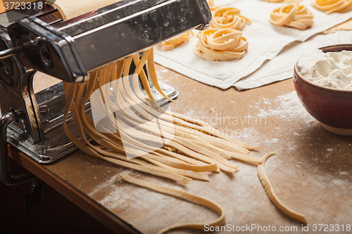 Image of The fresh pasta and  machine on kitchen table