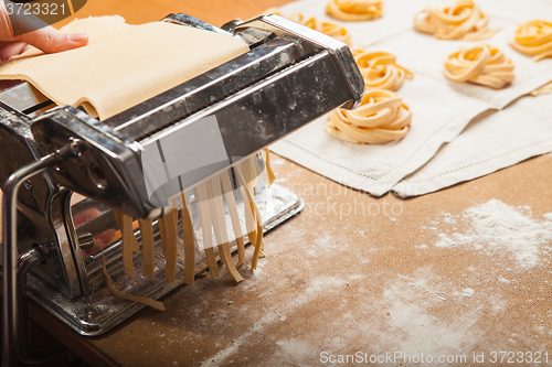 Image of The fresh pasta and  machine on kitchen table