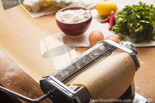 Image of The fresh pasta and  machine on kitchen table