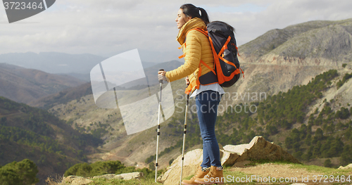 Image of Young woman hiker standing overlooking a valley