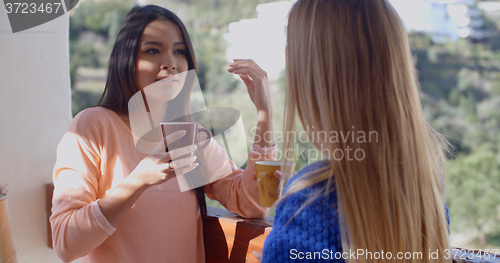 Image of Young woman drinking coffee and using a mobile