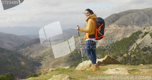 Image of Young woman hiker standing overlooking a valley