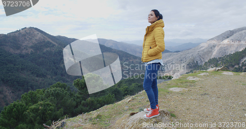 Image of Woman in yellow coat near mountain valley