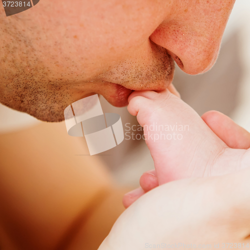 Image of father kisses the foot of baby.