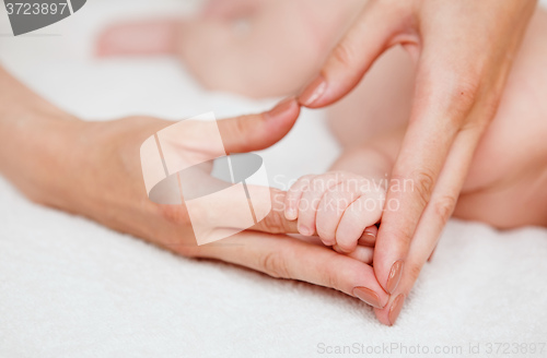 Image of Baby holding mother finger and together form heart shape by hand.