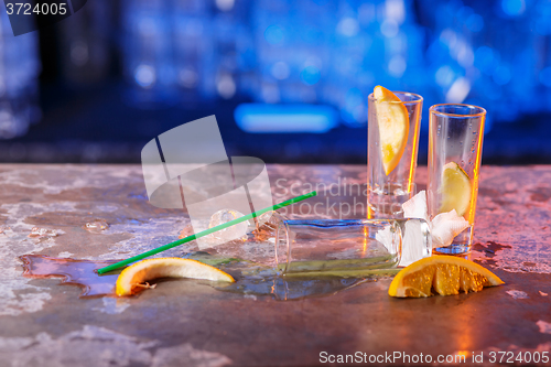 Image of The spilled cocktails with ice cubes on blue color in the bar